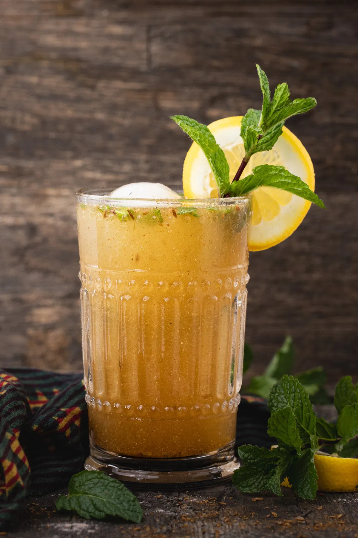 Chilled masala soda served in a tall glass with lemon wedges ,mint leaves and a sprinkle of chaat masala